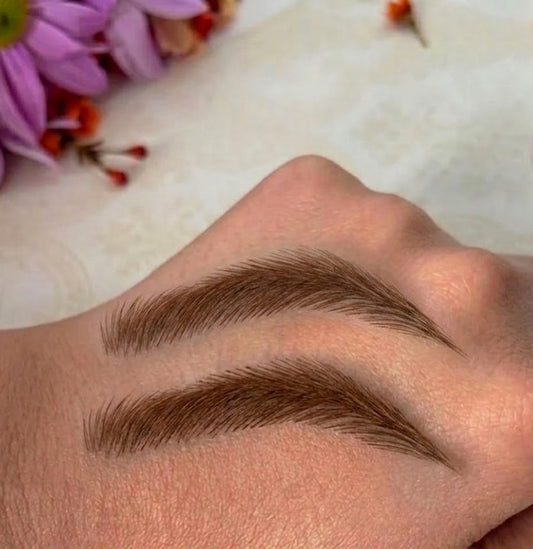 Eyebrow makeup swatch on a hand with flowers in the background