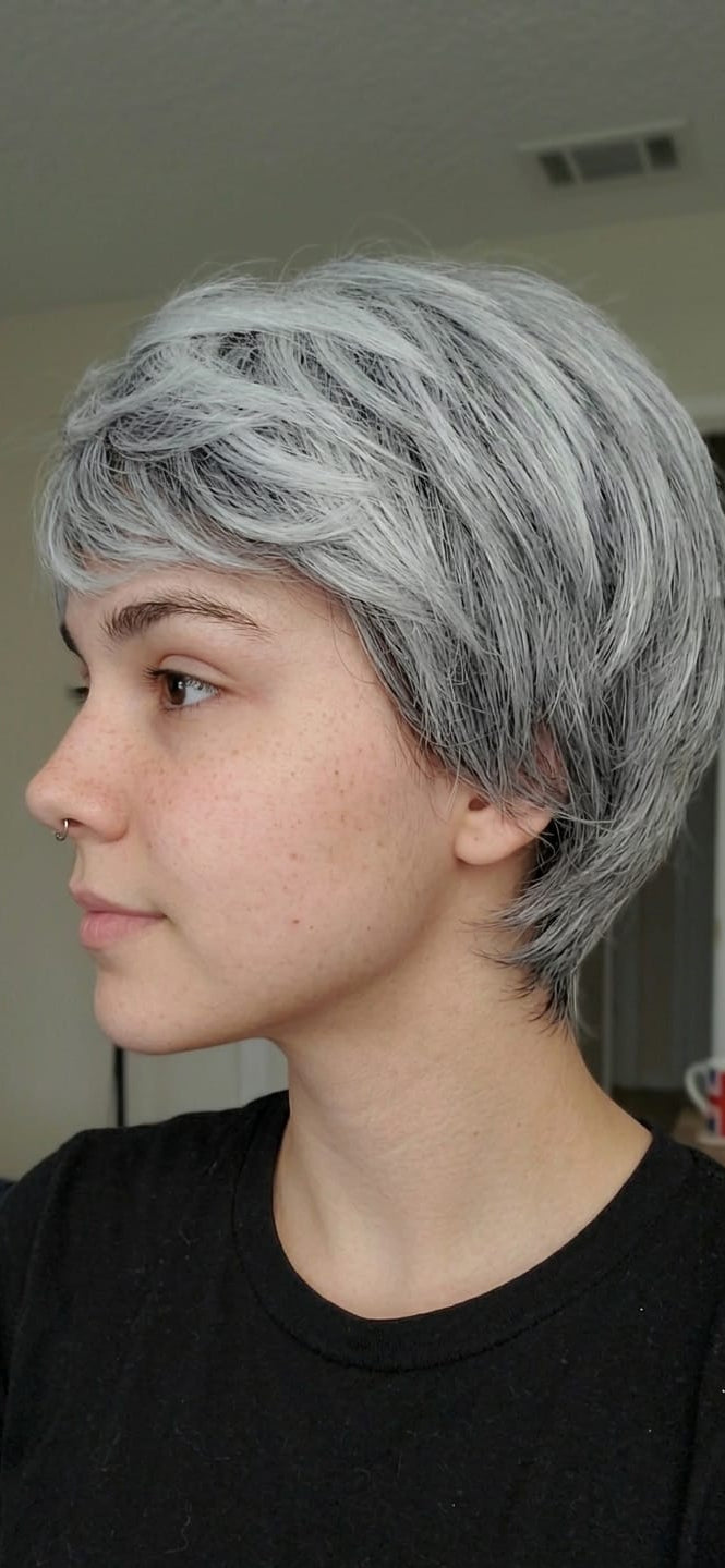 Person with short, styled hair in a neutral indoor setting