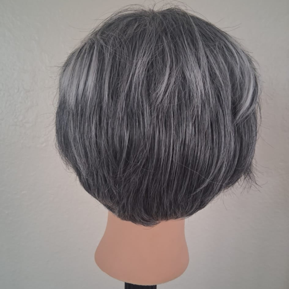 Gray wig on a mannequin head against a plain background