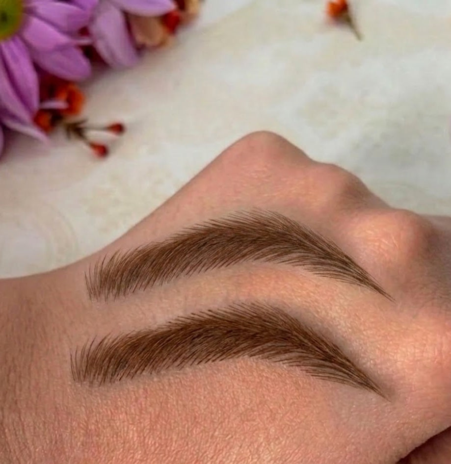 Eyebrow makeup swatch on a hand with flowers in the background