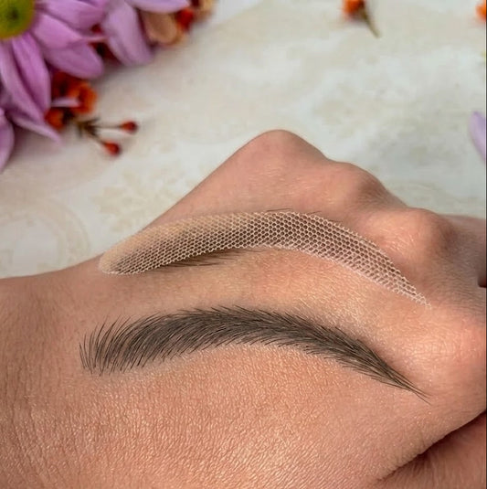 Eyebrow tattoo process on a person's hand with flowers in the background
