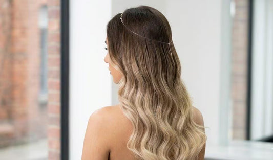Woman with wavy hair looking out a window with a blurred background